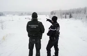 A Frontex official and a Finnish border guard stand near the closed Vaalimaa border station between Finland and Russia, on December 7. The Nordic country, which shares a 1,340km-long border with Russia, saw a surge in undocumented migrants seeking asylum on its border with Russia in November. [Alessandro Rampazzo/AFP]