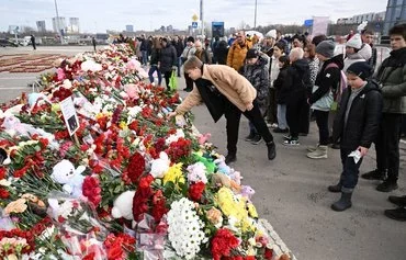 Mourners lay flowers at a makeshift memorial in front of the burnt-out Crocus City Hall concert venue in Krasnogorsk, outside Moscow, on March 26. [Natalia Kolesnikova/AFP]