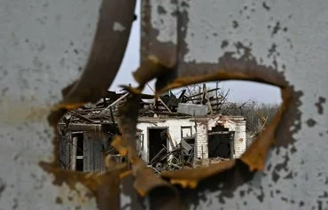 A destroyed private house seen through a shrapnel hole in the house gates in the village Velyka Pysarivka, which lies 5km from the Russian border, in Sumy province on March 24, amid the Russian invasion of Ukraine. [Genya Savilov/AFP]