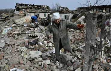 Svitlana Zavaly, 67, walks over the rubble of her house destroyed by a Russian bomb in the village Velyka Pysarivka, which lies 5km from the Russian border, in Sumy province on March 24, amid the Russian invasion of Ukraine. [Genya Savilov/AFP]