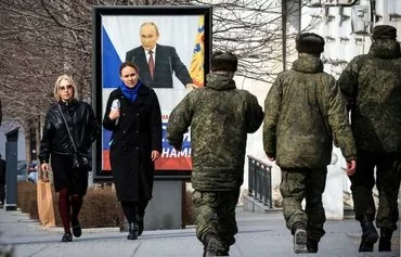 Pedestrians walk in front of a poster showing Russian President Vladimir Putin and reading 'The West doesn't need Russia. We need Russia!' in Simferopol, Crimea, on March 5. [AFP]