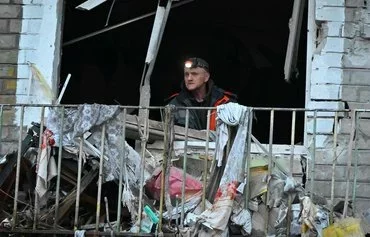 A man clears debris in his flat in a residential building damaged as a result of Russian strikes in Kharkiv on March 27, amid the Russian invasion in Ukraine. [Sergey Bobok/AFP]