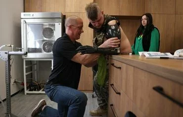 Veronika Kucherenko, watches as upper limb prosthetist James Allan adjusts her husband's bionic arm prosthesis at the Protez Foundation in Kyiv, on April 2, amid the Russian invasion in Ukraine. [Anatolii Stepanov/AFP]