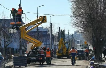 Workers fix power lines on Vokzalna Street in Bucha, Ukraine, northwest of Kyiv, on March 30, 2023. [Sergei Supinsky/AFP]