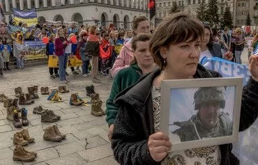 Родственники и друзья украинских солдат, пропавших без вести в боях против российских войск, держат портреты близких на митинге с требованиями к властям принять меры. Киев, 13 апреля. [Роман Пилипей/AFP]