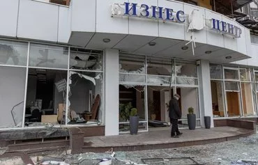 A man stands on the porch of a business center damaged by a missile attack in Odesa on March 26. [Oleksandr Gimanov/AFP]