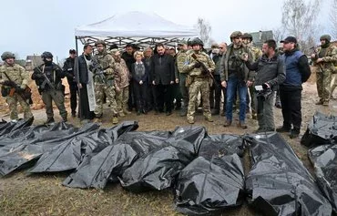 European Commission President Ursula von der Leyen is flanked by then-Slovak Prime Minister Eduard Heger and European Union foreign policy chief Josep Borrell as they visit a mass grave in the town of Bucha, Ukraine, northwest of Kyiv, on April 8, 2022. [Sergei Supinsky/AFP]