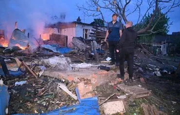 Local residents inspect the remains of their destroyed house after a Russian drone attack in the suburbs of Kharkiv on May 21 amid the Russian invasion in Ukraine. [Sergey Bobok/AFP]