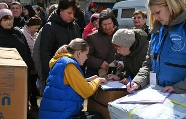 Local residents queue to receive humanitarian aid in Kharkiv on April 6 amid the Russian invasion in Ukraine. [Sergey Bobok/AFP]