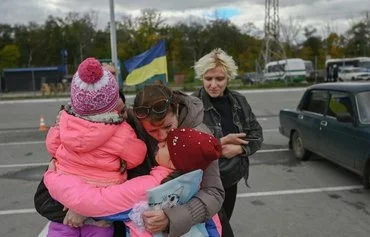 A Ukrainian woman and her children October 21, 2022, are welcomed in Zaporizhzhia by a relative after they left Russian-occupied territory in Kherson province amid Russia's invasion of Ukraine. [Bulent Kilic/AFP]