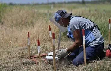 A deminer from the HALO Trust NGO clears mines in a field outside the village of Snigurivka, Mykolaiv province, Ukraine, on June 4 amid the Russian invasion of Ukraine. [Genya Savilov/AFP]