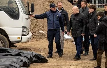 International Criminal Court Prosecutor Karim Khan (4th right) visits a mass grave in Bucha, Ukraine, on the outskirts of Kyiv, on April 13, 2022, amid Russia's invasion of Ukraine. [Fadel Senna/AFP]