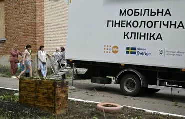 Women wait for an appointment next to a mobile gynecology clinic in Novomykolaivka village, Donetsk province, on June 13, amid the Russian invasion of Ukraine. [Genya Savilov/AFP]