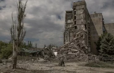 A local resident pushes a bicycle past a destroyed apartment building following shelling in Toretsk, Donetsk province, on June 25, amid the Russian invasion of Ukraine. [Roman Pilipey/AFP]