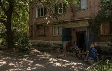 Residents sit outside an apartment building in Toretsk, Donetsk province, on June 22, amid the Russian invasion of Ukraine. [Roman Pilipey/AFP]