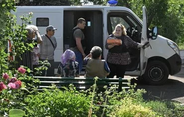 Postwoman Ganna Fesenko (right), 39, sets up boxes of newspapers, coffee, pasta and cookies at a first stop of her route in the central square of the village of Novoselydivka, Donetsk region, on June 14. [Genya Savilov/AFP]