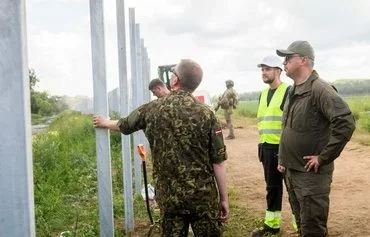 Latvian President Edgars Rinkevics (left) inspects the construction of a wall in Karsava, Latvia, along the border with Russia, on June 18. [Gints Ivuskans/AFP]