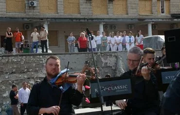 Medical personnel listen to the Kyiv Classical Chamber Orchestra performing music during the July 12 event 'Requiem for the Fallen' to commemorate the victims of the Russian attack on the country's largest children's hospital, Okhmatdyt, in Kyiv. [Anatolii Stepanov/AFP]