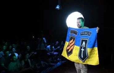 A moderator presents a flag with signatures of soldiers of the Ukrainian 3rd Assault Brigade for an auction during their meeting with members of the Ukrainian diaspora in Warsaw on July 21 as part of a multi-city European tour. [Sergei Gapon/AFP]