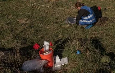 An ecological investigator collects soil in the area that was flooded following the Kakhovka dam explosion, for an investigation into allegations of Russian ecocide, in Chornobaivka village, outskirts of Kherson, last November 7. Russia is suspected of blowing up the dam June 6, 2023. [Roman Pilipey/AFP]