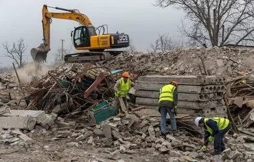 Former Ukrainian soldiers, now employees of French company Neo-Eco, work to clear debris of a school destroyed by Russian bombing in the village of Lyubomyrivka, Mykolaiv province, on February 14. Ukraine and Neo-Eco plan to recycle the debris. [Oleksandr Gimanov/AFP]