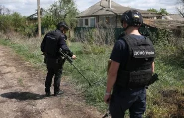 Employees of the State Emergency Service of Ukraine search for land mines in the village of Dovhenke, Kharkiv province, on April 23. [Anatolii Stepanov/AFP]