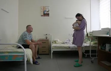 Rescuer Vitaly, 29, sits in front of his wife Kateryna, 30, holding their daughter Dasha, who was born 9 days before, in the ward of the Perinatal Center of Pokrovsk, Donetsk region, on July 20. [Anatolii Stepanov/AFP]