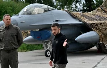 Ukrainian President Volodymyr Zelenskyy stands in front of an F-16 fighter jet during a ceremony marking Ukrainian Air Force Day at an undisclosed location on August 4. [Sergei Supinsky/AFP]