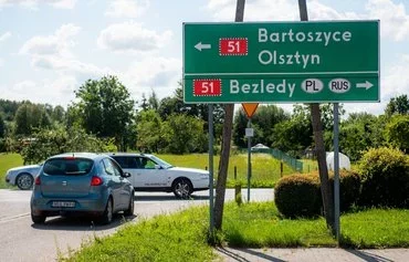 Cars head past a road sign indicating the direction to the Bezledy crossing at the Polish-Russian border in the Polish village of Bezledy, Warmian-Masurian region, on August 1. [Mateusz Slodkowski/AFP]