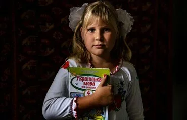 Antonina, 9, September 1, 2022, at home in Pokrovske village holds a Ukrainian language schoolbook after an online lesson on the first day of the 2022-2023 school year amid the Russian invasion of Ukraine. [Dimitar Dilkoff/AFP]