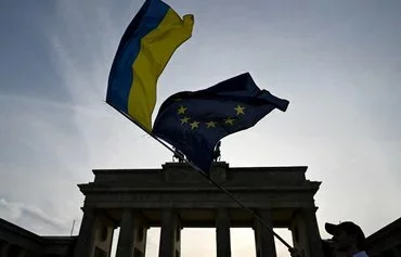 An activist waves the Ukrainian flag and the European Union flag in front of Brandenburg Gate in Berlin last August 24 during a concert to mark Ukraine's Independence Day. [John Macdougall/AFP]