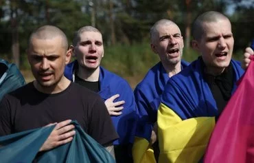 Ukrainian troops sing their national anthem after their release from Russian captivity at an undisclosed location near the Ukrainian-Belarusian border on September 13. [Anatolii Stepanov/AFP]