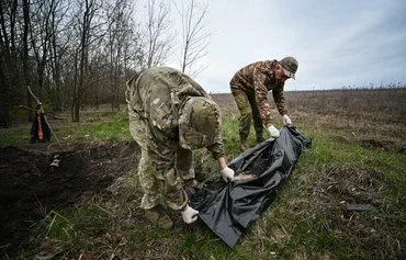 Члены украинской группы гражданско-военного сотрудничества укладывают в мешок тело российского солдата. Харьковская область, 11 апреля 2023 г. [Сергей Бобок/AFP]