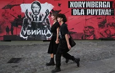 A couple walks past a banner depicting Russian President Vladimir Putin and reading 'Killer' and 'Nuremberg for Putin' in Wroclaw, Poland, on September 20. [Sergei Gapon/AFP]