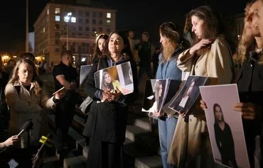 Colleagues of the late Ukrainian journalist Victoria Roshchyna hold photographs of her during an event in her memory at a makeshift memorial for fallen Ukrainian soldiers in Kyiv on October 11. [Anatolii Stepanov/AFP]