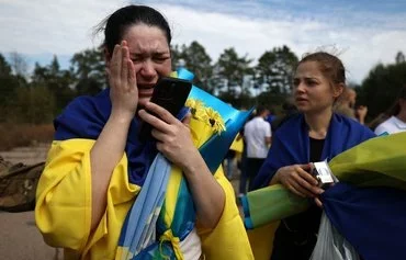 A Ukrainian servicewoman talks on the phone to her children after her release from Russian captivity at an undisclosed location near the Ukrainian-Belarusian border, on September 13. [Anatolii Stepanov/AFP]