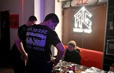 People look at merchandise and insignia from the Ukrainian 3rd Assault Brigade and a linked youth group, Centuria, during the Saturday night rave party in a former silk factory in Kyiv on November 9. [Sergei Supinsky/AFP]