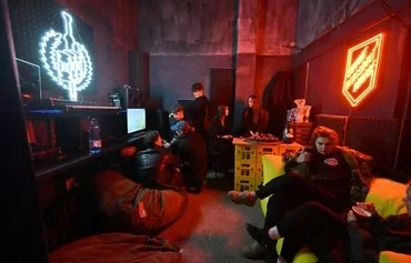 People learn how to fly a combat drone on a simulator during the Saturday night rave party in a former silk factory in Kyiv on November 9, aimed at raising funds for the Ukrainian 3rd Assault Brigade. [Sergei Supinsky/AFP]