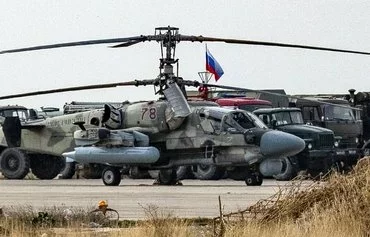 A Russian military attack helicopter is pictured with other trucks and vehicles at the Russian air base at Qamishli Airport in Syria on December 12. [Delil Souleiman/AFP]