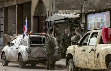 Russian soldiers stand by military pickups as they prepare to evacuate a position in Qamishli, Syria, on December 12. [Delil Souleiman/AFP]