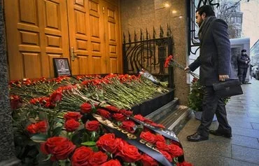 A man lays flowers outside Azerbaijan's embassy in Moscow on December 26, paying tribute to the victims of Azerbaijan Airlines' plane crash. [Alexander Nemenov/AFP]