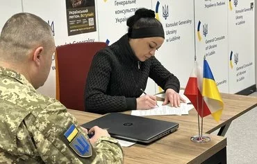 Оne of the three woman recruits, 44-year-old Lesya Nesterenko, signs a contract to join the Ukrainian Legion January 10 in Lublin, Poland. [Ukrainian Consulate in Lublin]