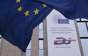 A banner announcing Poland's assumption of the rotating presidency of the Council of the European Union is seen beside an EU flag in Brussels on January 6. Poland's six-month term began January 1. [Nicolas Tucat/AFP]