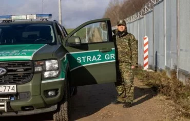 Michal Bura, a spokesman for the Podlasie region border guards, stands next to his car on the border road in Minkowce village, Podlasie region, Poland, November 15. [Wojtek Radwanski/AFP]