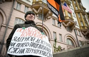 Пропутинский активист на одиночной демонстрации перед посольством США в Москве 5 ноября с плакатом «Мы поддерживаем изменение ядерной доктрины, чтобы позволить перенацелить ядерное оружие на США!» в день выборов президента США. [Александр Неменов/AFP]