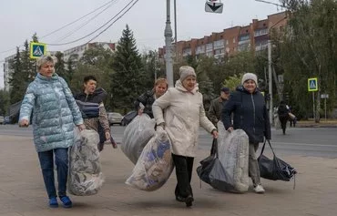 Женщины несут гуманитарную помощь в центре Курска 18 октября. [Андрей Бородулин/AFP]