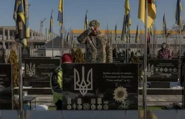 A Ukrainian military member grieves at the grave of a Ukrainian soldier at a cemetery, in Bucha, northwest of Kyiv on February 24, on the third anniversary of Russia's invasion of Ukraine. [Roman Pilipey/AFP]