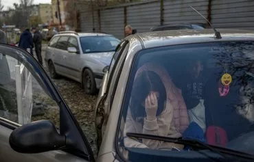 A Ukrainian woman sits in a car with her family November 5, 2022, in Zaporizhzhia, Ukraine, after they fled Russian-occupied territory in Ukraine. [Bulent Kilic/AFP]