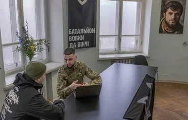 A member of the Da Vinci Wolves Battalion speaks with a recruit during the opening of the battalion's recruiting center, in Kyiv, on February 10, 2024. [Roman Pilipey/AFP]