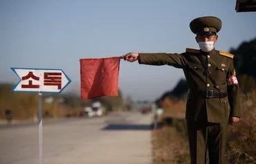 In this photo taken on October 29, 2020, a North Korean public security officer uses a red flag to stop a taxi for disinfection as part of preventive measures against COVID-19, on a road at the entrance to Wonsan, Kangwon province. [Kim Won Jin/AFP]